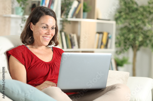 Happy adult woman watching content on laptop at home Free Download Happy adult woman watching content on laptop at home - GFXLoad