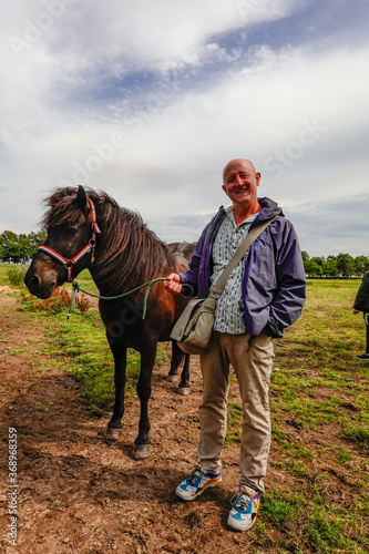 Helgenaes, Denmark A man stads with a horse ready for horsebackriding