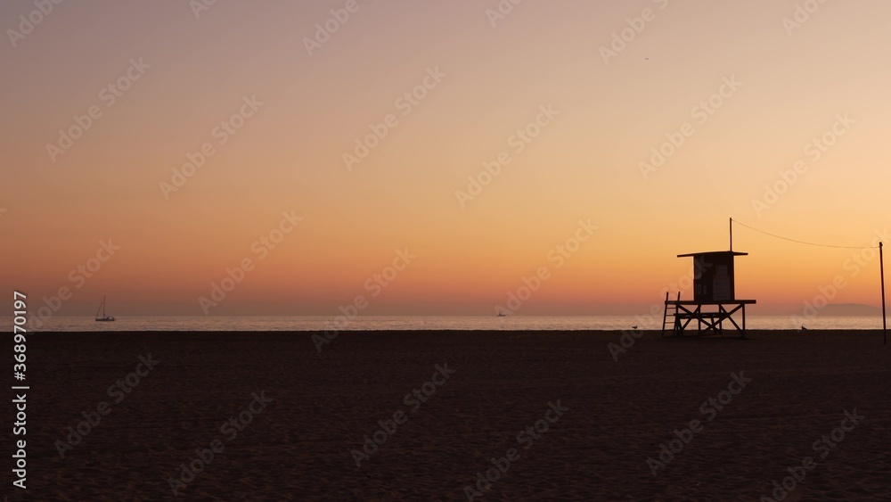 Summertime travel concept. Dark silhouette, iconic retro wooden lifeguard watch tower against sunset orange sky. Contrast watchtower outline, california pacific ocean beach twilight aesthetic, CA USA Summertime travel concept. Dark silhouette, iconic retro wooden lifeguard watch tower against sunset orange sky. Contrast watchtower outline, california pacific ocean beach twilight aesthetic, CA USA
