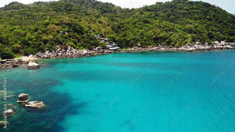 Calm sea near tropical volcanic island. Drone view of peaceful water of blue sea near stony shore and green jungle of volcanic Koh Tao Island on sunny day in Thailand.