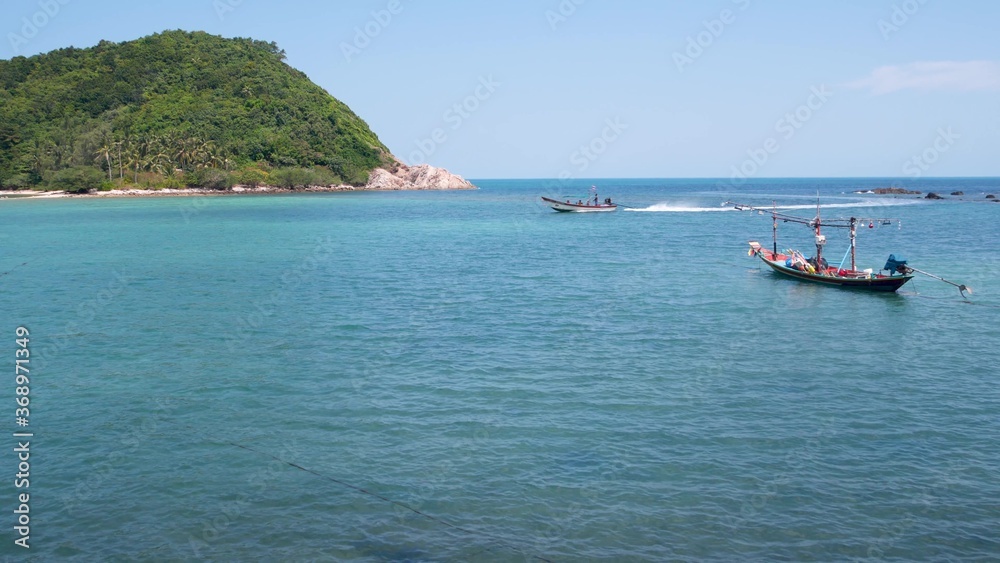 Boat on shore near waving sea. Traditional boat on sunny day on tropical exotic Koh Phangan, Thailand. Paradise Koh Ma Island.