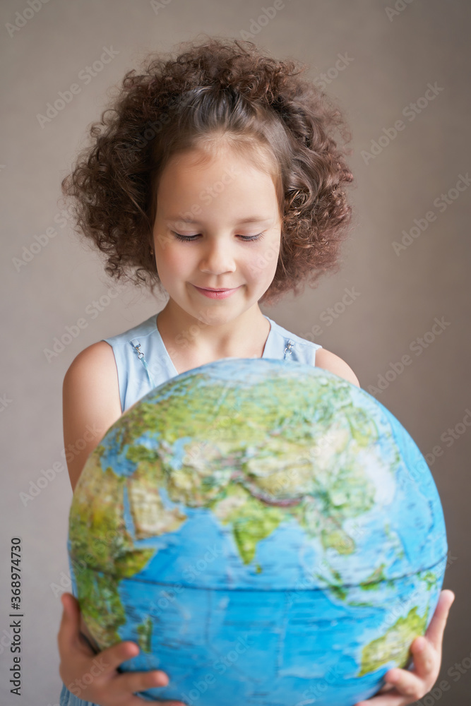 children's day. a beautiful curly-haired girl holds the planet. children's day. a beautiful curly-haired girl holds the planet.