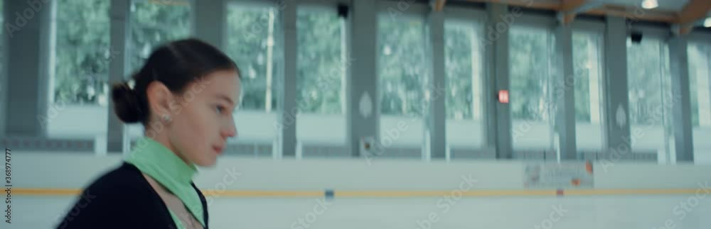 Female ice figure skater falls on ice while practicing jumps on the rink. Shot on RED cinema camera with 2x Anamorphic lens, 75 FPS slow motion