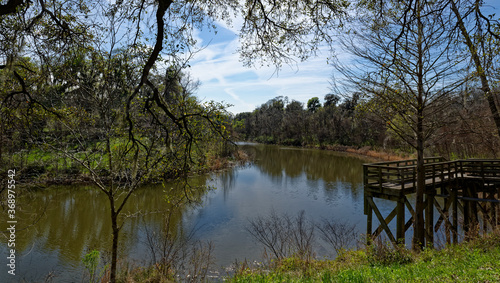A wooden Pier or Viewpoint at a bend in the River Brazos, at Brazos Bend State Park in Texas, under a sunny blue sky in March.