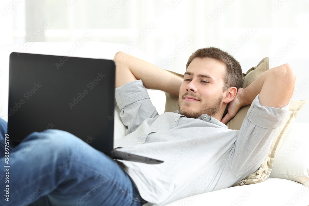 Relaxed man watching video on laptop lying at home Relaxed man watching video on laptop lying at home