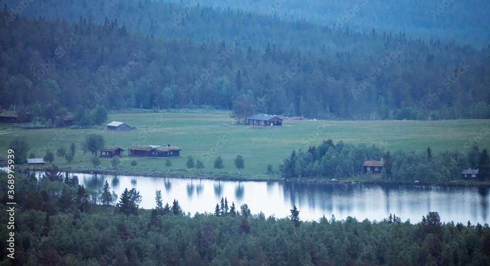 Foggy mountain layers and cabins during blue hour and sunset. Peaceful and tranquil scenery.