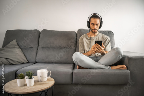 Konstfotografi Hombre con moño, barba, camiseta verde suave y vaqueros azul claro escuchando mú