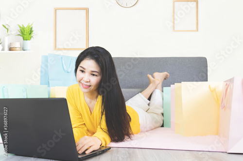 Online shopping concept. Happy young asian woman with laptop making online shopping and many shopping bag ,e-commerce order from home,online payment of financial management © Ann Patchanan