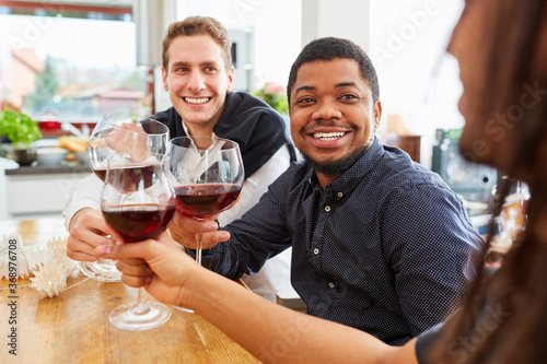 Group of men drinking and clinking glasses of wine as friends