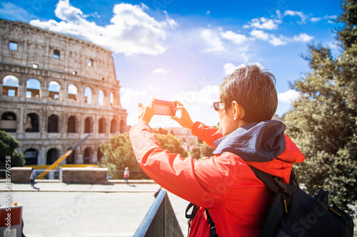 Photography Selective focus of back view asian blogger tourist with backpack which he's take a picture by smartphone at Colosseum in Rome, Italy