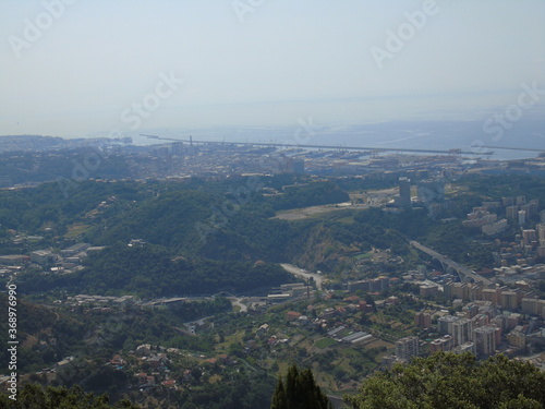 Genova, Italy – 07/30/2020: Beautiful scenic aerial view of the city, port, dam, sea, Cristoforo Colombo airport runway, containers shipping terminal, Pra, Voltri, and Sestri promontory from Monte Gaz