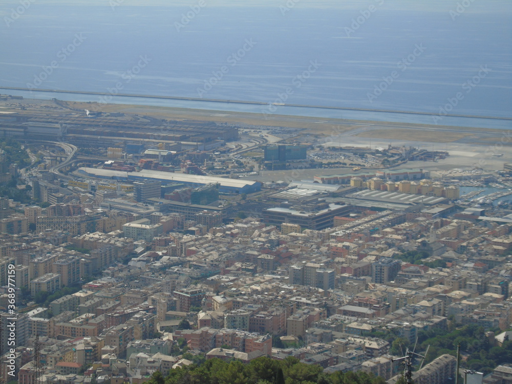 Genova, Italy – 07/30/2020: Beautiful scenic aerial view of the city, port, dam, sea, Cristoforo Colombo airport runway, containers shipping terminal, Pra, Voltri, and Sestri promontory from Monte Gaz