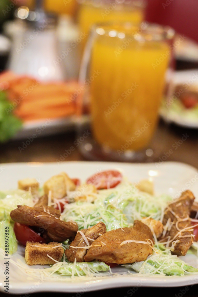Caesar salad in the restaurant and orange juice. Caesar salad with chicken.