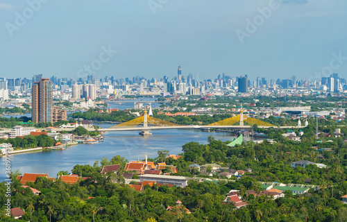Aerial view of Maha Chesadabodindranusorn Bridge or Nonthaburi Bridge crossing Chao Phraya River and Bangkok skyline, Thailand. Urban city and downtown with skyscraper buildings. photo
