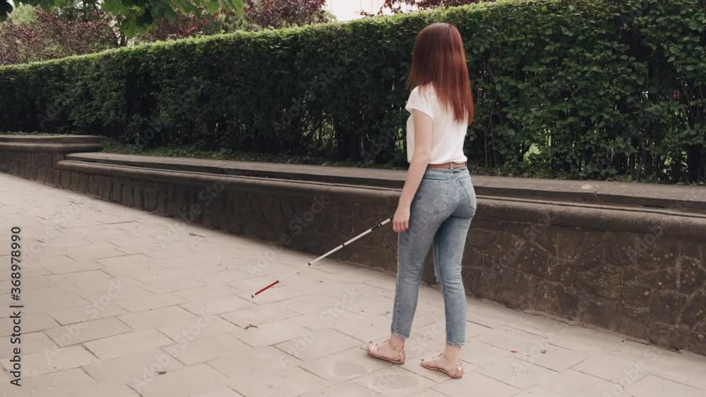 Blind woman is walking on the sidewalk in city. Woman using a white cane. Blind woman is walking on the sidewalk in city. Woman using a white cane.