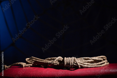 Skein of rope for role-playing games on a red leather couch. BDSM concept. A lace for the Japanese art of shibari. No people.