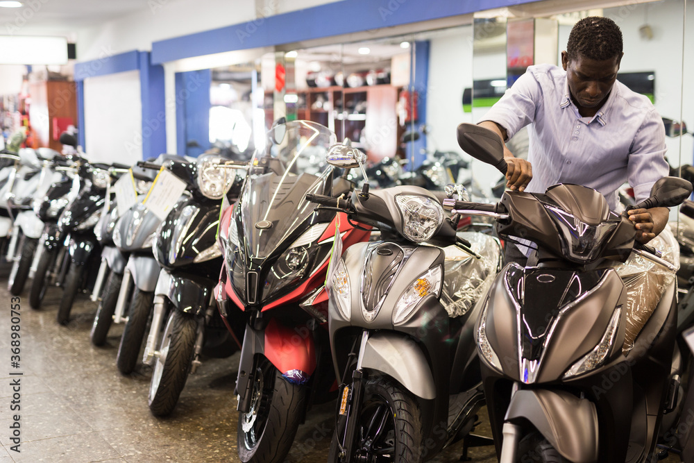 Portrait of adult man buying new motorcycle at modern showroom. High quality photo