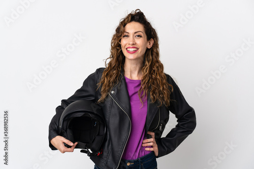 Young caucasian woman holding a motorcycle helmet posing with arms at hip and smiling