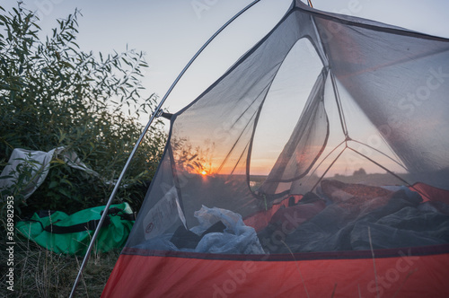 The sunset is visible through the tent, the mosquito net is stretched over the aluminum frame,