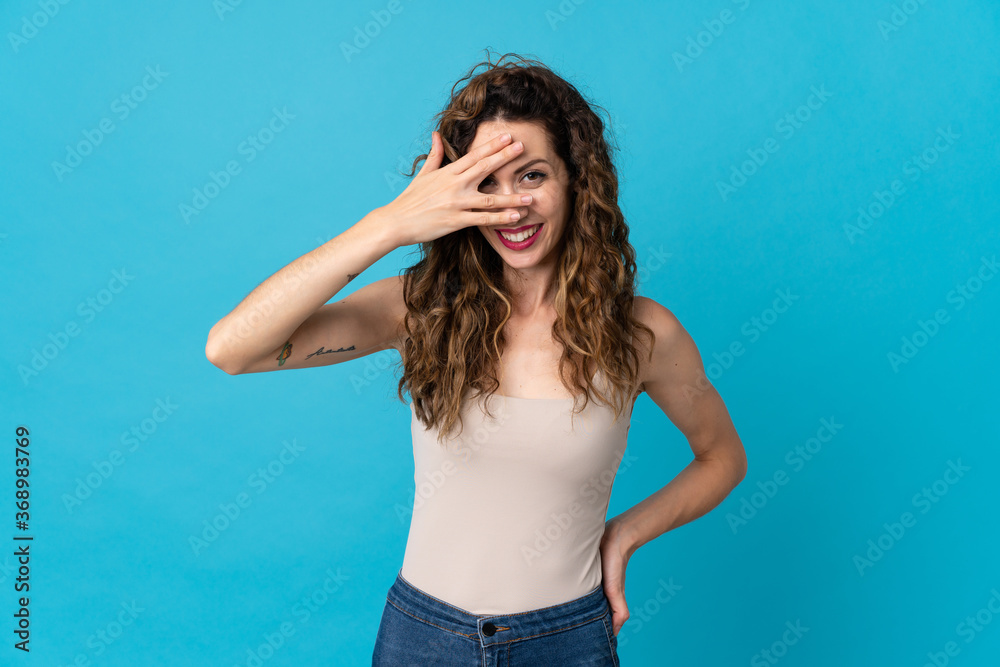 Young caucasian woman isolated on blue background covering eyes by hands and smiling Young caucasian woman isolated on blue background covering eyes by hands and smiling