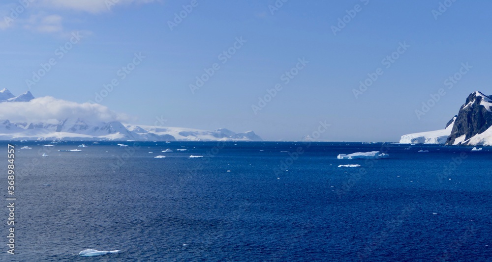 Antarctic ocean landscape, icebergs, clouds on mountain with glacier, Antarctica