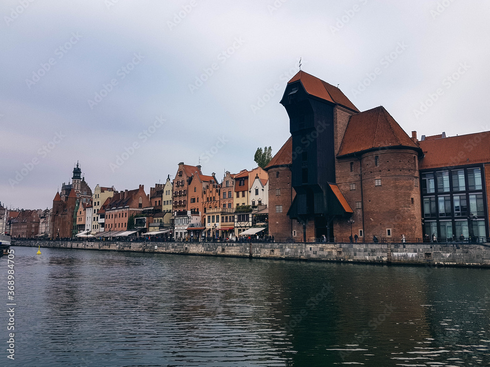 Naklejka premium The main landmark of Gdansk, the Gdansk Crane and houses on the bank of the river Motlawa.