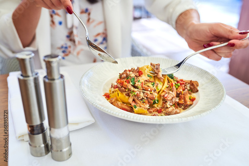 Woman eating pasta with chanterelles and chorizo in a restaurant