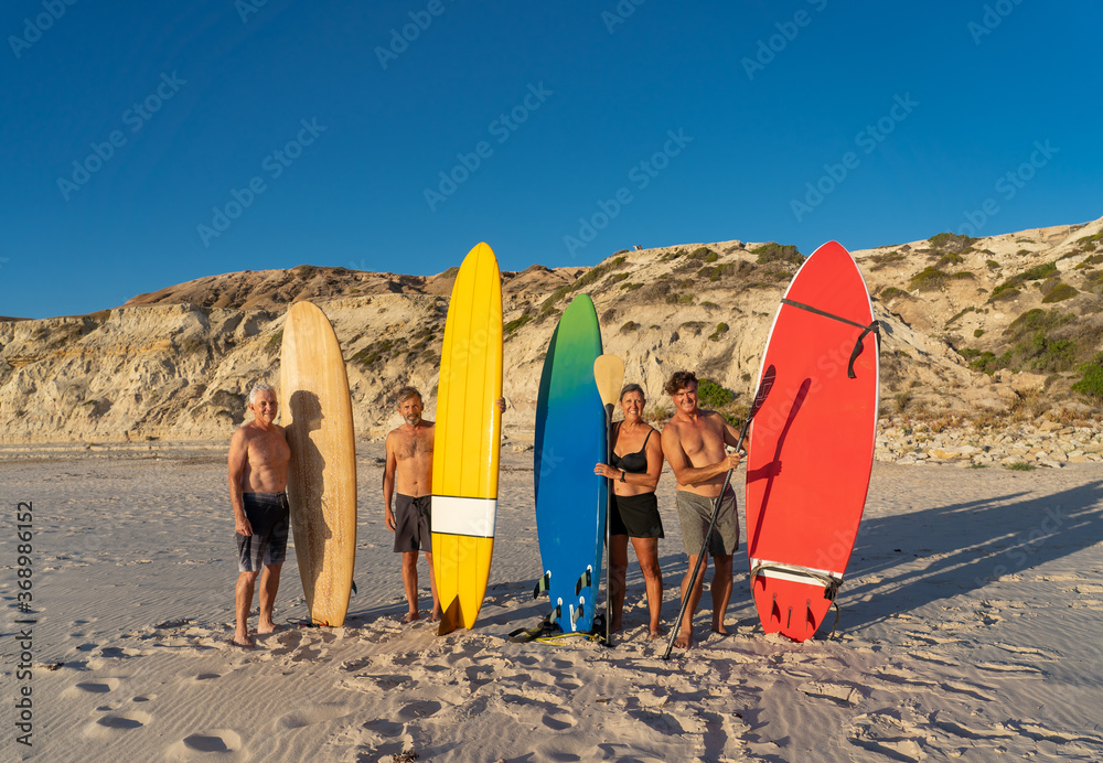 Portrait of group of mature men and woman surfers holding their surfboards on beach Portrait of group of mature men and woman surfers holding their surfboards on beach