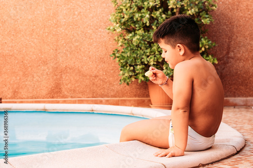 happy little boy in the pool while eating an ice cream