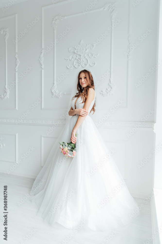The first meeting of the groom in a black suit and the bride in a white wedding dress with a bouquet in the interior of a photo studio on a white and black background The first meeting of the groom in a black suit and the bride in a white wedding dress with a bouquet in the interior of a photo studio on a white and black background