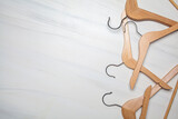 Empty wooden clothes hangers on white marble background. Top view, copy space.