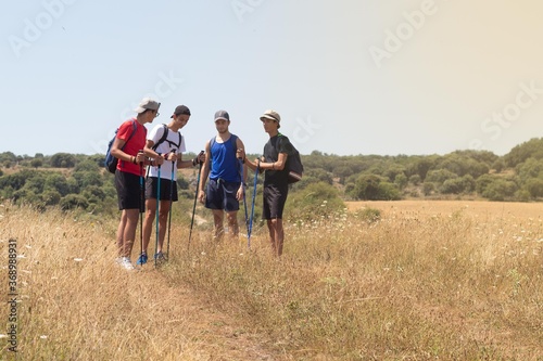young people talking during a walk with the trekking sticks through the countryside and the Camino de Santiago