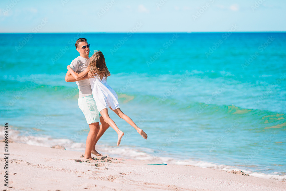 Little girl and happy dad having fun during beach vacation Little girl and happy dad having fun during beach vacation