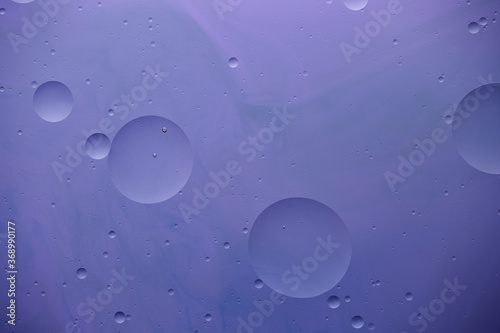 Current collection of brilliant backgrounds for your design. Close-up shot of water circles and drops on violet paint with blue stains.