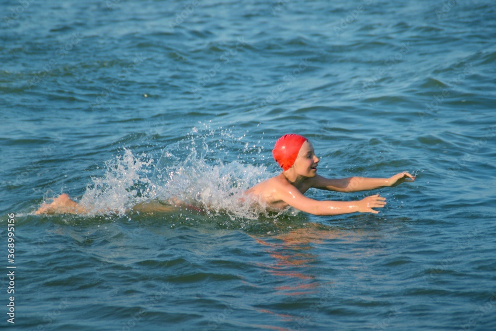 The child happily swims on the sea waves