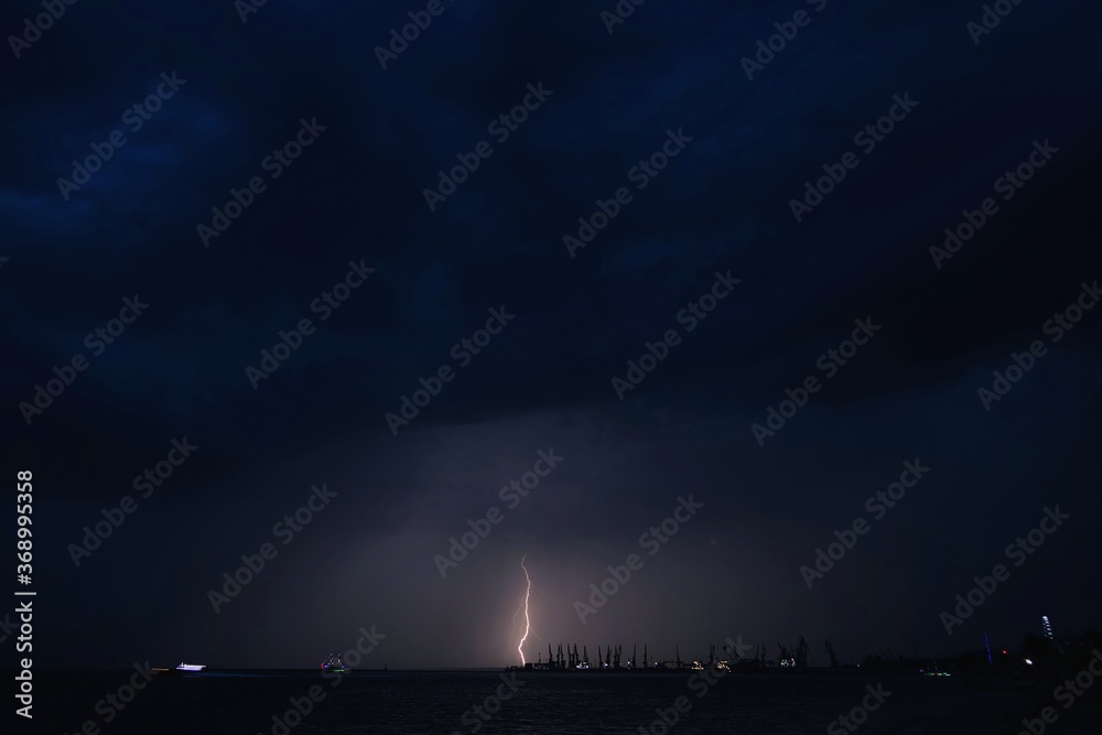 Lightning and storm clouds in the night sky over the sea Lightning and storm clouds in the night sky over the sea