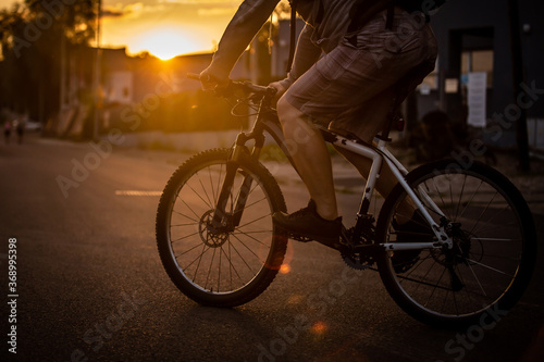 A man riding a bicycle with a sunset background.