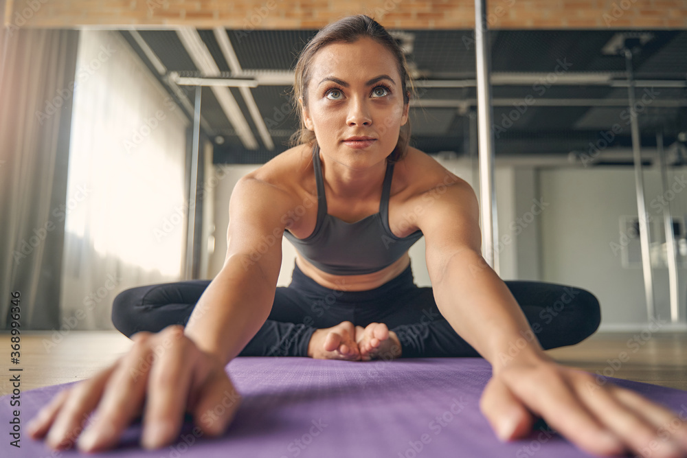 Beautiful young woman sitting on yoga mat Beautiful young woman sitting on yoga mat