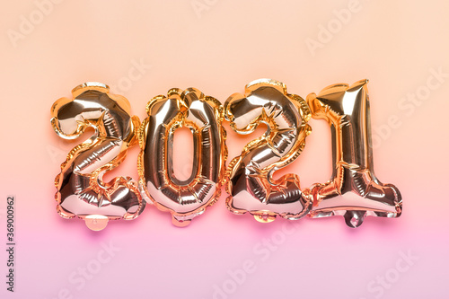 Gold foil balloons numeral 2021 isolated on beige background Flat lay creative composition Top view Happy New year 2021, Merry Christmas concept Holiday card