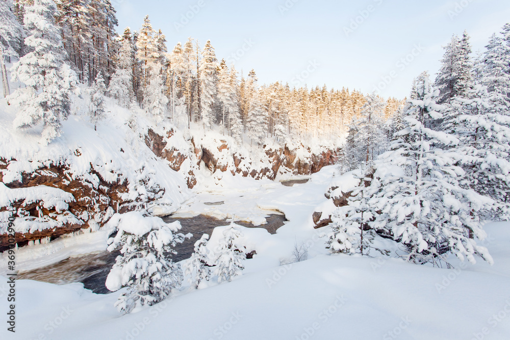 Oulanka National Park. Kiutaköngäs rapids with red rock wall during a cold and snowy evening near Kuusamo in Finnish wild nature, Northern Europe. 