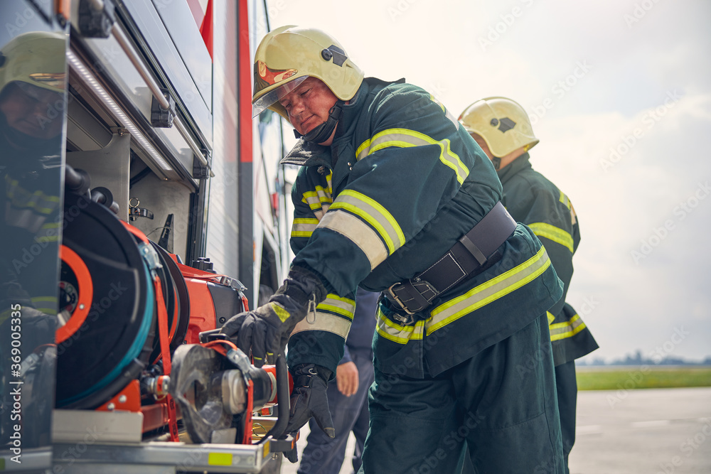 Fototapeta premium Firefighter installing equipment on the fire machine