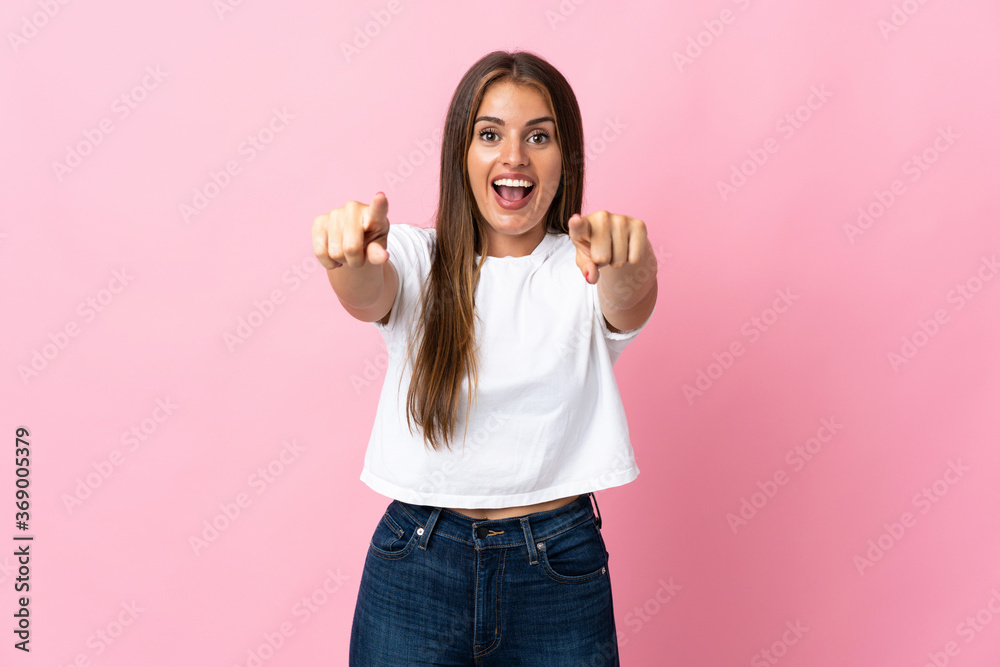 Young Uruguayan woman isolated on pink background surprised and pointing front Young Uruguayan woman isolated on pink background surprised and pointing front