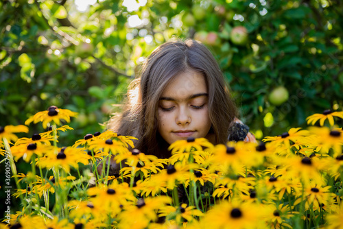 Portrait of a beautiful smiling girl outdoor. Girl in a field of yellow flowers. Young girl with long hair with flowers. summer morning. Garden