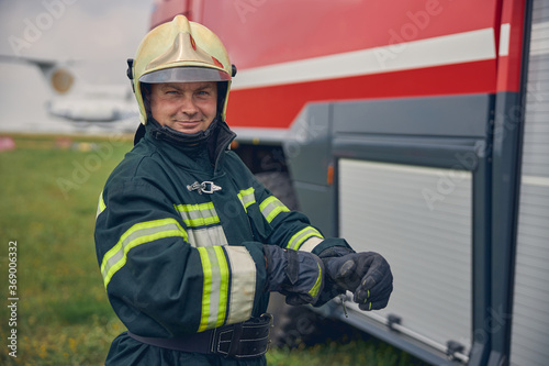 Smiling firefighter in yellow helmet and protective gloves standing in the outdoors