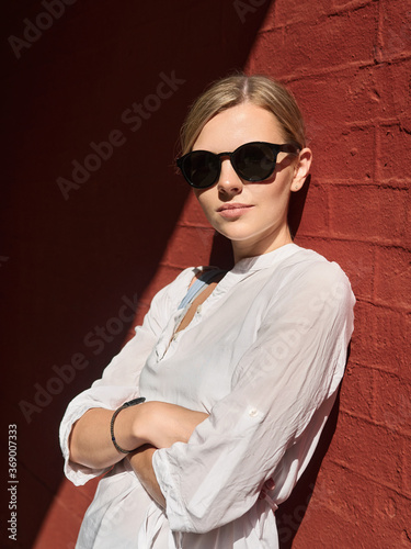 Outdoor summer city lifestyle portrait of young trendy dressed blonde happy woman in sunglasses having fun outdoor in the city ready for travel