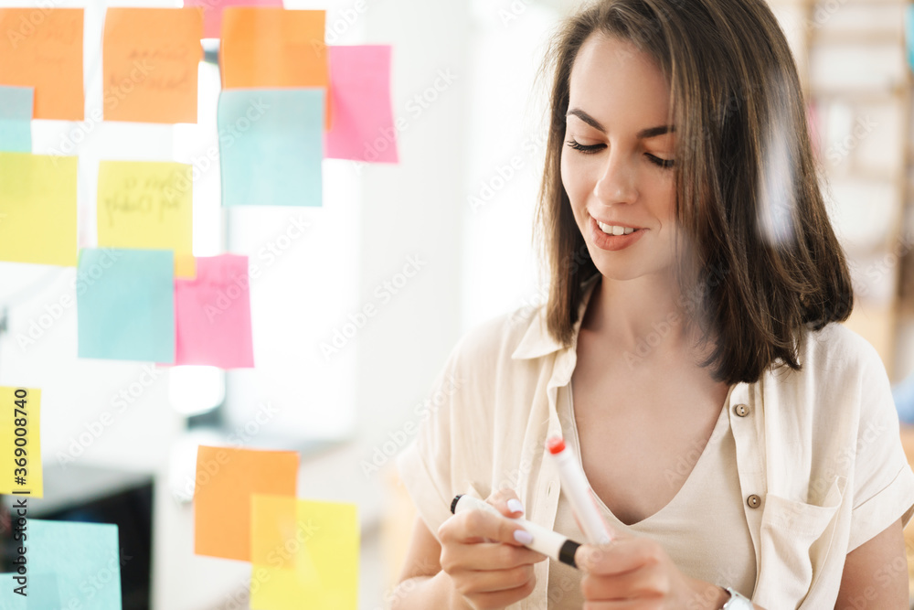 Image of young beautiful smiling woman using marker pen and stickers Image of young beautiful smiling woman using marker pen and stickers