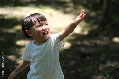 close up one Asian toddler raising arm to the sunshine. blur background
