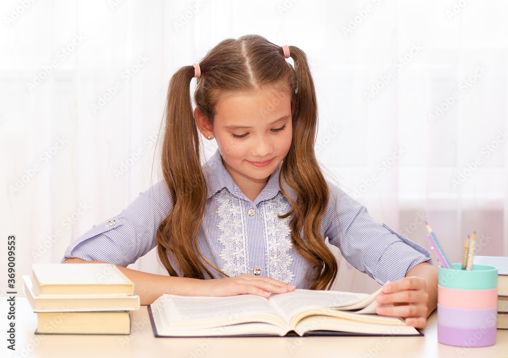 Education and school concept. Child is sitting at the desk and reading a book. Education and school concept. Child is sitting at the desk and reading a book.