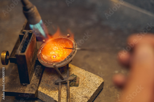 Jeweler melting the metal placed in a crucible photo