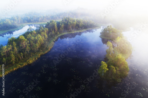 An aerial view of summery foggy morning in Mukri bog in Estonia with some small bog lakes and islands in Northern Europe.  © adamikarl